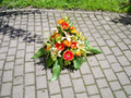 Sarggesteckesteck in rot/gelb gehalten (Lilien, Gerbera und Rosen)